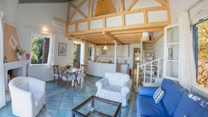 Un vaste espace de vie doté d’un haut plafond, d’une table à manger, d’un canapé et d’un escalier menant à un niveau supérieur.