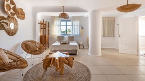 Ein geräumiges Zimmer mit einem großen Bett, Korbsesseln und einem runden Holztisch.