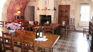 A rustic dining room with a stone wall, a fireplace, and a chandelier. - Enchanting Château with en-suites, Pool, Tennis, Grand Piano, BBQ, Fast WiFi (Thézac)