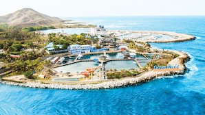 An aerial view of Ocean World resort with multiple pools, a beach area, and a mountainous backdrop. - A Few Steps From The Gorgeous Beach Of Punta Rucia! (Punta Rucia)