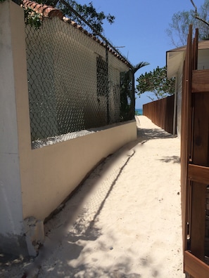Guests can stroll along the beachfront pathway, flanked by fences, to reach the sandy beach.