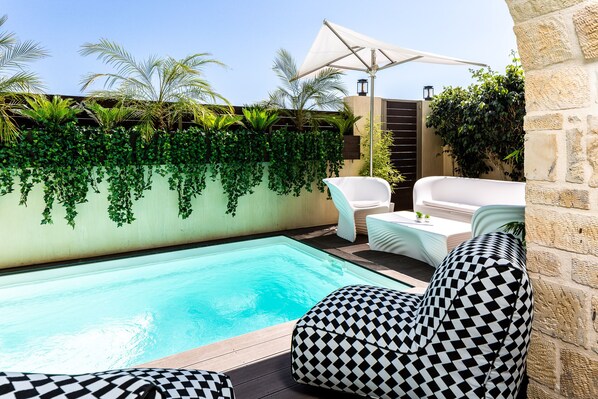 A pool area with a checkered sofa, a small table, and an umbrella. - Villa Nayana - Shoreline Calm by etouri (Rethymno)