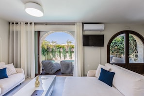 Une chambre d’hôtel comprenant un lit, deux canapés, une télévision et un balcon avec des meubles d’extérieur.