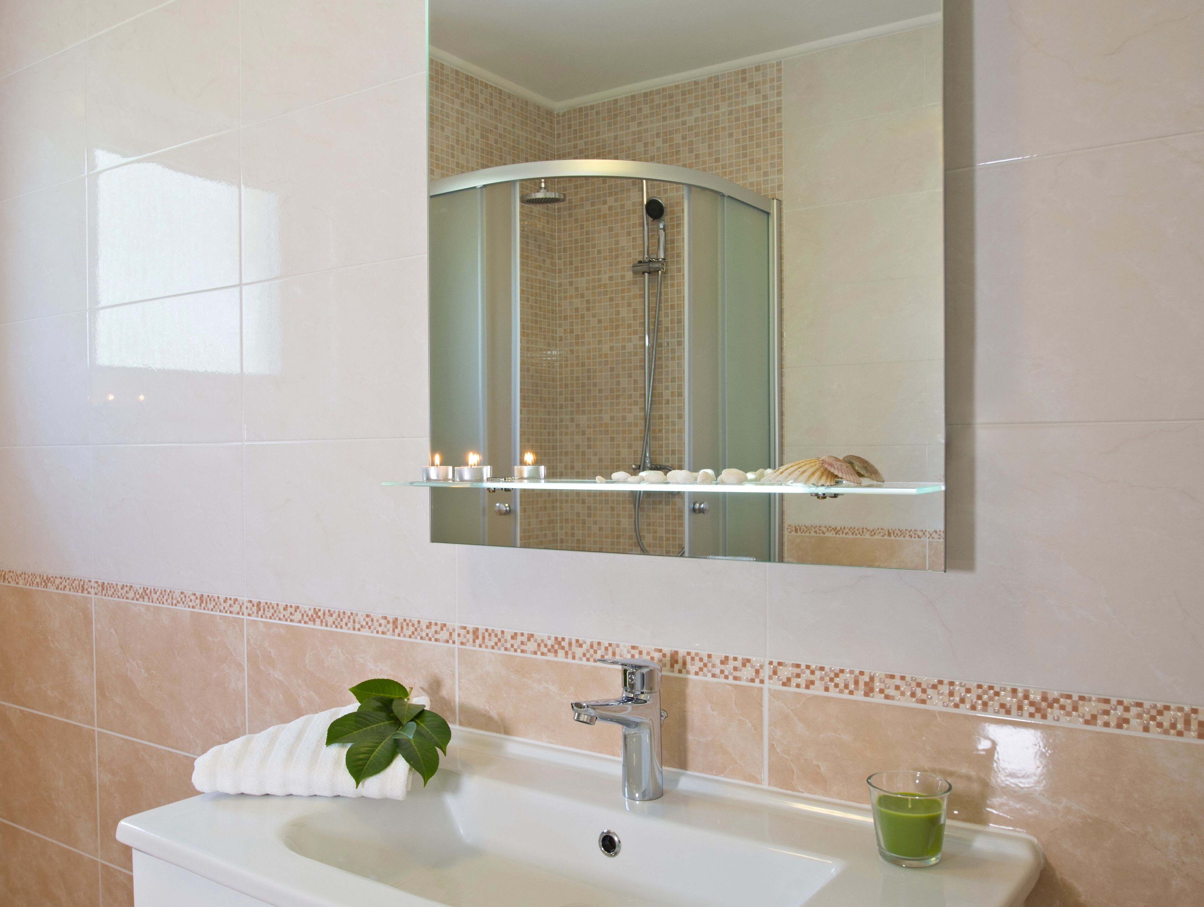 A bathroom with a sink, mirror, and shower.