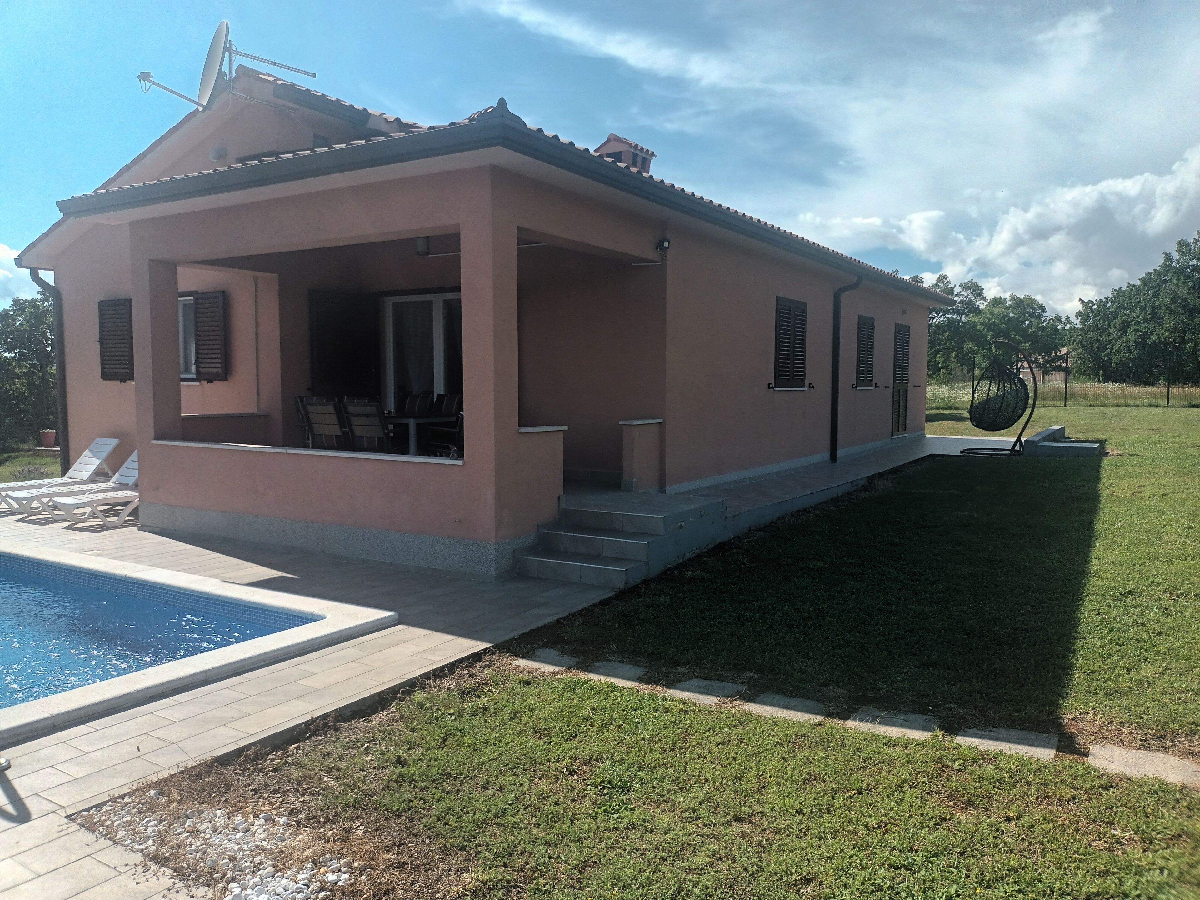 A two-story house with a covered patio, a swimming pool, and a well-maintained lawn.