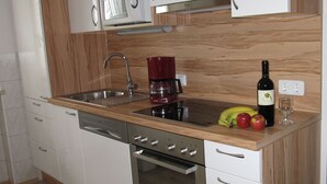 Une cuisine dotée d’un plan de travail en bois, d’appareils électroménagers en acier inoxydable, d’une machine à café, d’une bouteille de vin et d’un verre.