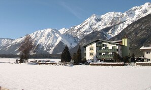 A hotel with a traditional Alpine architectural style, featuring a prominent balcony and a view of snow-covered mountains. - Adlerhof am Sonnenplateau Vacation Rental in Mieming, Pet-Free for People with Allergies (Mieming)