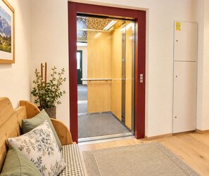 An elevator with a wooden interior, a checkered rug, and a plant on a wooden bench.