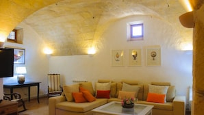 Un salón acogedor con techo de piedra, un conjunto de sofá, una mesa de centro y cuadros enmarcados en la pared.