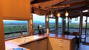 Een keuken met een groot raam, een houten aanrecht en uitzicht op het landschap.