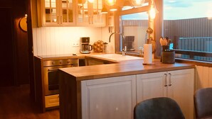 Een keuken met houten kastjes, een centraal eiland en hanglampen.