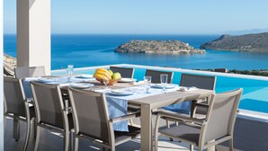 A dining table set for four with a view of the sea and a rocky island. - Amazing Sea View to Spinalonga Island - 3 bedroom villa (Elounda)