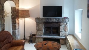 Un salon doté d’une cheminée en pierre, d’un canapé en cuir, d’une table basse et d’un téléviseur fixé au-dessus de la cheminée.