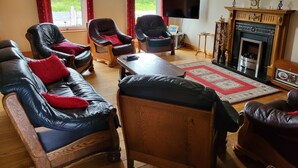 A living room with leather sofas, a wooden coffee table, a fireplace, and a television. - Spectacular Views, Miles of Beaches, and Boat Trips, 4 Star  Luxury Home (Dingle)