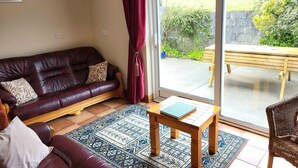 A living room with a dark brown leather sofa, a wooden coffee table, and a patterned rug. - Spectacular Views, Miles of Beaches, and Boat Trips, 4 Star  Luxury Home (Dingle)