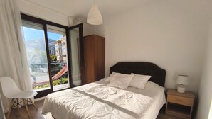 A bedroom with a bed, a chair, a nightstand, and a view of a balcony. - Bright 1BR apartment with two balconies, mountain views, sea glimpses and PKG (Будва)