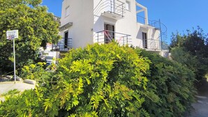 A modern two-story building with a white exterior, a balcony with a metal railing, and a sign indicating private property. - Bright 1BR apartment with two balconies, mountain views, sea glimpses and PKG (Будва)