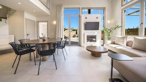 A spacious living area with a dining table, black chairs, a sofa, and a TV. - Luxury, Spacious Villa with private gym, just 4km from the sandy beach! (Πηγή)