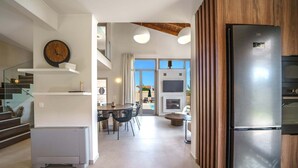 A modern kitchen with a built-in refrigerator, a dining area with a round table and chairs, and a staircase leading to an upper level. - Luxury, Spacious Villa with private gym, just 4km from the sandy beach! (Πηγή)