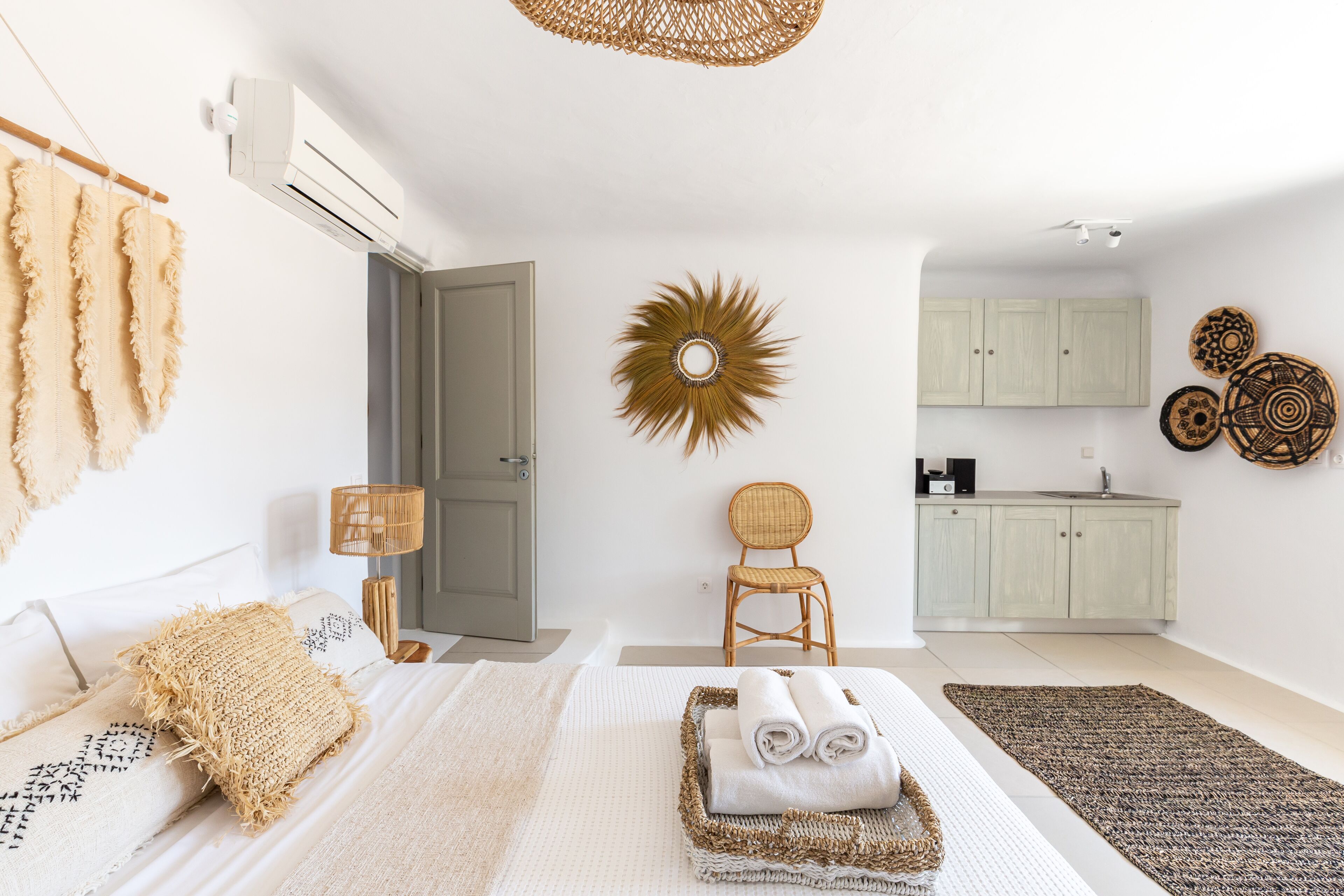 Une chambre moderne comprenant un lit, une chaise, une petite table et un coin cuisine.