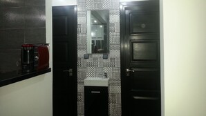 A bathroom with a black and white tiled backsplash, a small sink, and two doors. - Flat three rooms furnished and equipped with air conditioning and wifi satelite (Agadir)