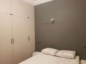 A bedroom with a bed, a wardrobe, and a wall with a decorative item.
