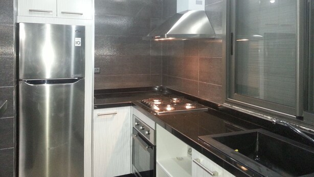 A modern kitchen with stainless steel appliances, dark tiles, and a large window. - Flat three rooms furnished and equipped with air conditioning and wifi satelite (Agadir)
