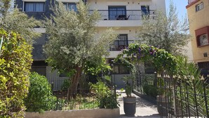 A modern multi-story residential building with balconies, surrounded by greenery and a metal fence. - Flat three rooms furnished and equipped with air conditioning and wifi satelite (Agadir)