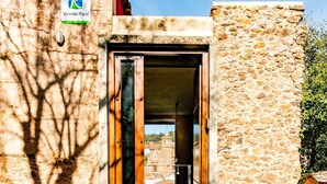 Edificio rústico de piedra con puerta de madera y espacio interior a la vista.