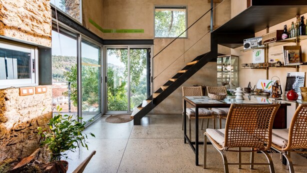 Un interior moderno con escalera, comedor y ventanas amplias que ofrecen vistas a zonas verdes.