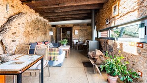 Un interior rústico con paredes de piedra, vigas de madera, un sofá, una mesa y una planta en maceta.
