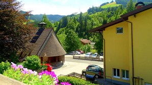 A yellow building with a sloped roof, a small gazebo, and a parking area with cars. - Haus Schneeberg - Aberg - Family apartment sleeping up to 5 people, with Hochkönig Card (Mühlbach am Hochkönig)