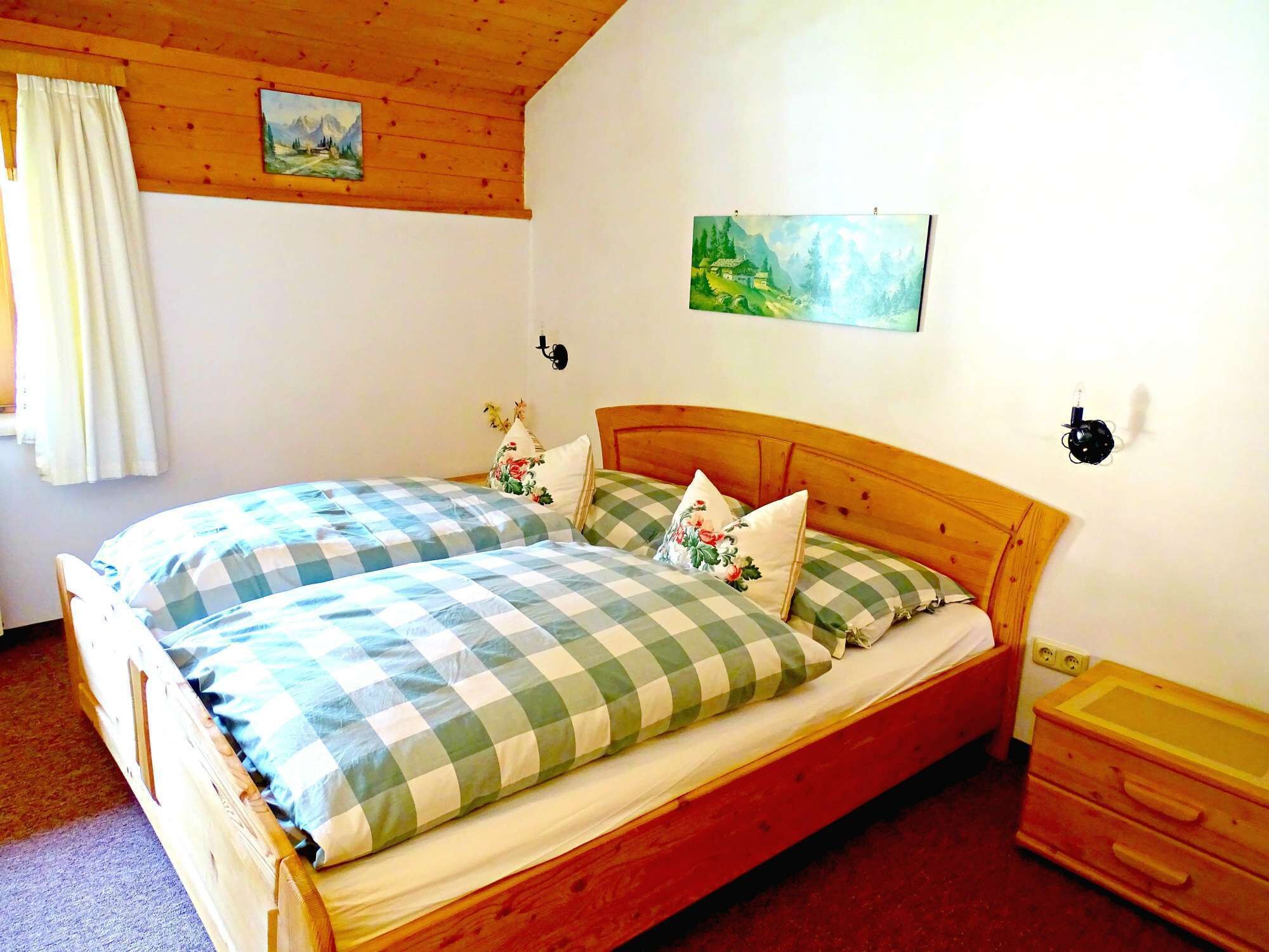 A wooden bed with checkered bedding, a wooden headboard, and a nightstand with drawers.