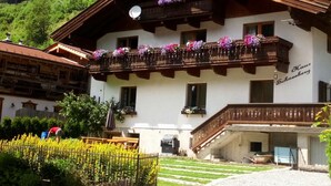 A traditional chalet with a balcony adorned with flowers, a satellite dish, and a sign reading "Haus Schneeburg". - Haus Schneeberg - Aberg - Family apartment sleeping up to 5 people, with Hochkönig Card (Mühlbach am Hochkönig)