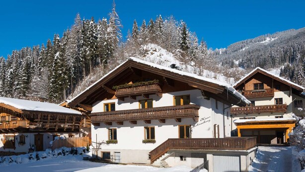 A traditional chalet-style building with multiple balconies, a wooden facade, and a snow-covered landscape. - Haus Schneeberg - Aberg - Family apartment sleeping up to 5 people, with Hochkönig Card (Mühlbach am Hochkönig)