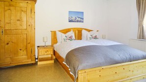 A bedroom with a wooden bed, a nightstand, a wooden wardrobe, and a framed picture on the wall. - Haus Schneeberg - Aberg - Family apartment sleeping up to 5 people, with Hochkönig Card (Mühlbach am Hochkönig)