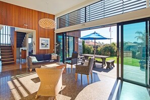 Ein großzügiger Wohnbereich mit modernem Design, mit einem großen Glasfenster, das auf eine Terrasse im Freien führt.