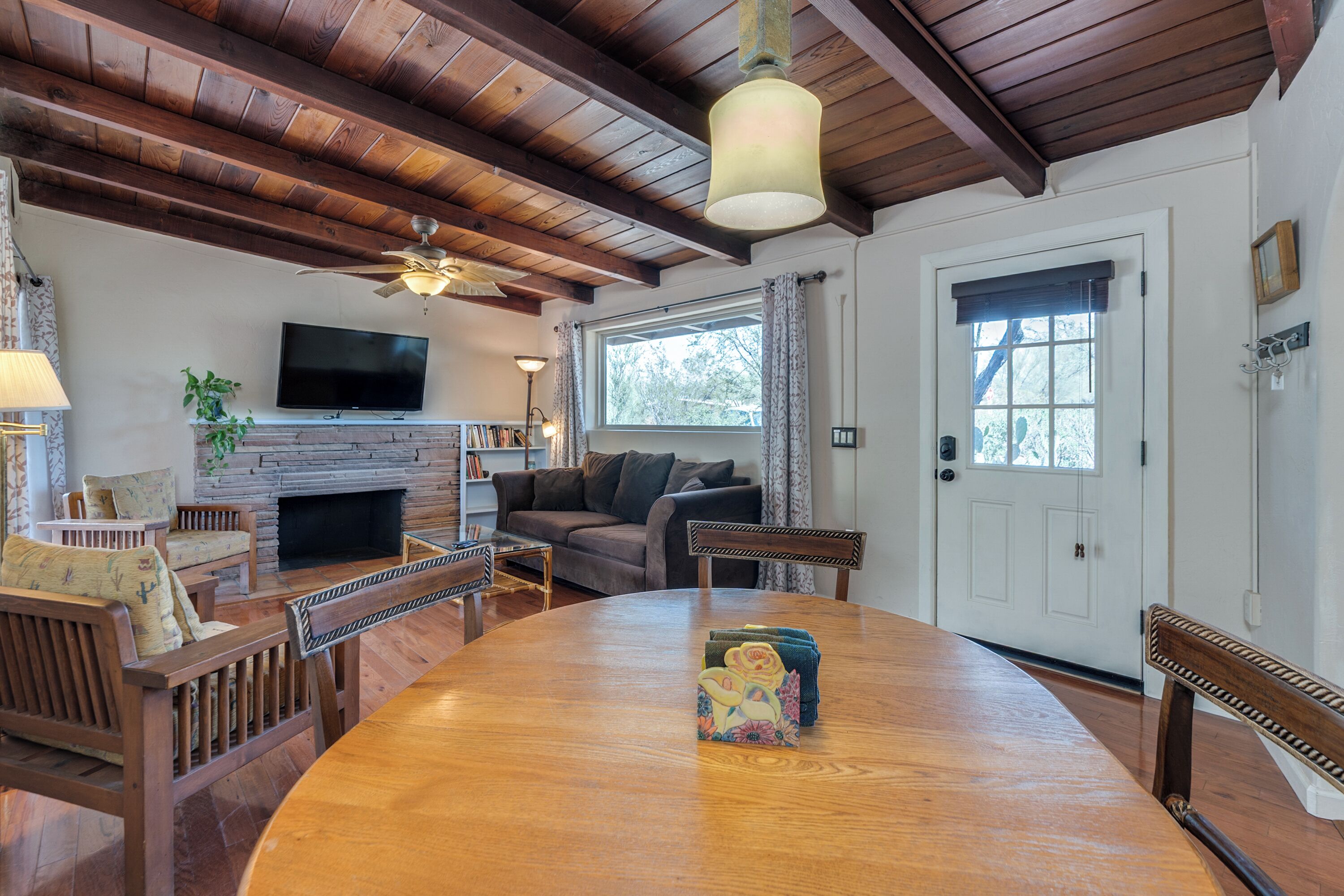 A cozy living room with a fireplace, wooden furniture, a television, and a dining table.