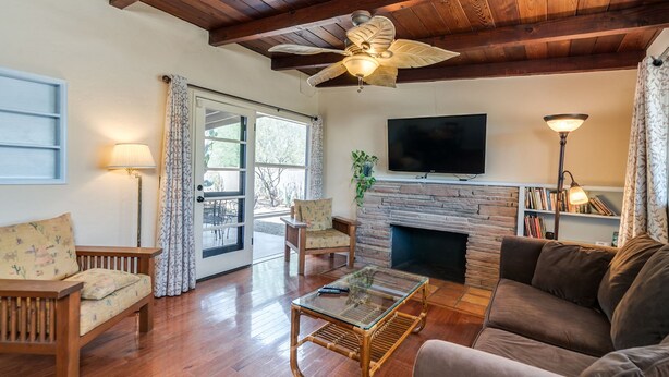 A living room with a wooden ceiling, a fireplace, a television, and a bookshelf. - Serene and Charming, Private, Immaculate, Central,  2/1.5 Back yard and Pool (Tucson)