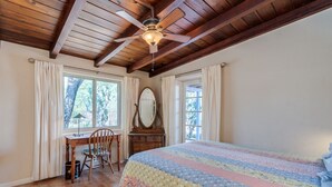 A bedroom with a wooden ceiling, a bed with a colorful quilt, a desk with a chair, and a dresser. - Serene and Charming, Private, Immaculate, Central,  2/1.5 Back yard and Pool (Tucson)
