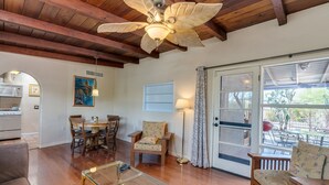 A spacious living area with wooden flooring, a ceiling fan, a dining table with chairs, a sofa, and a glass coffee table. - Serene and Charming, Private, Immaculate, Central,  2/1.5 Back yard and Pool (Tucson)