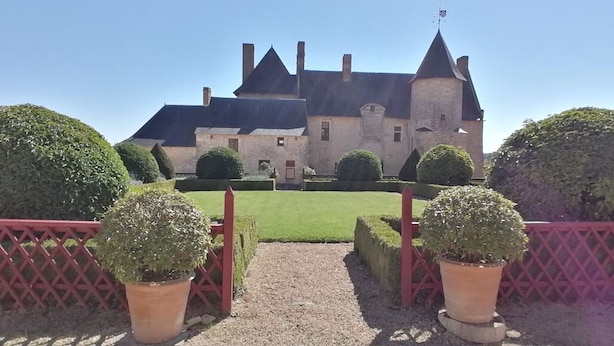 Un edificio de estilo castillo con un camino de grava que conduce a una puerta roja.