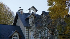 Un edificio grande e histórico con un tejado de gran pendiente y una torre destacada.