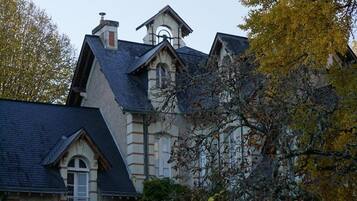 A large, historic building with a steeply pitched roof and a prominent tower.