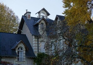 Un edificio grande e histórico con un tejado de gran pendiente y una torre destacada.