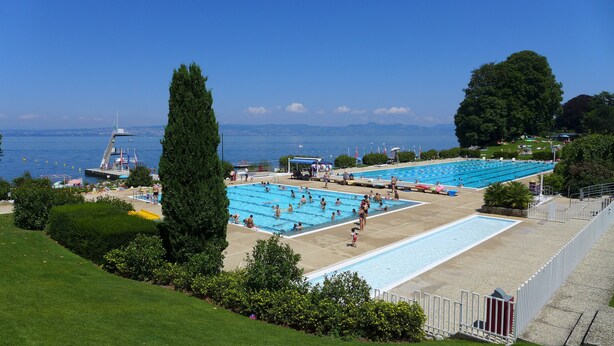 Un complexe de piscines comprenant plusieurs bassins, un poste de surveillance pour les sauveteurs et une vue sur la mer.
