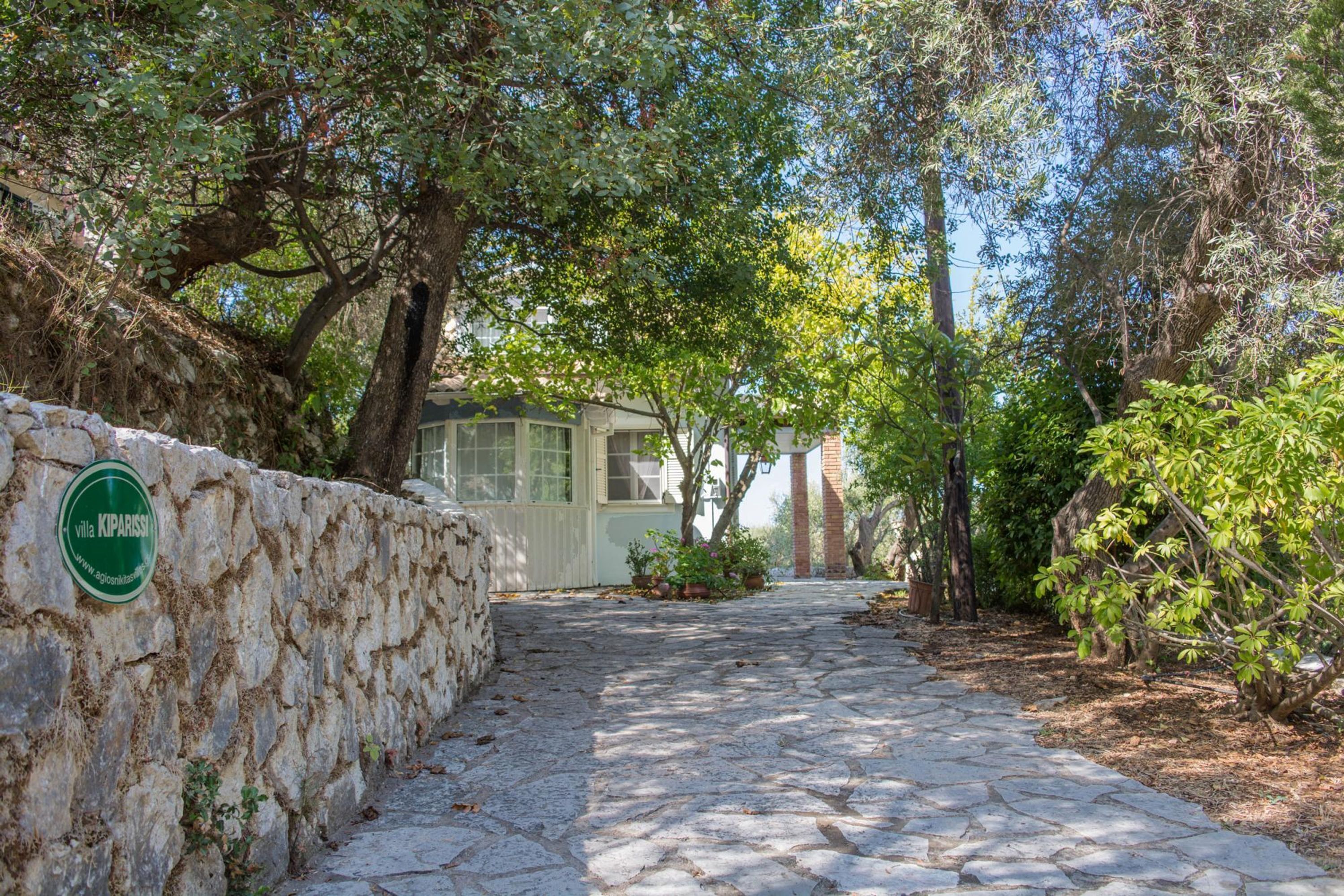 A stone pathway leading to a building with a green sign reading "Villa Kiparissa".