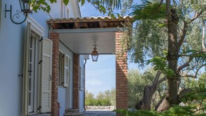 A stone-paved pathway leading to a building with a covered entrance and a lantern. - Villa Kiparissi - Agios Nikitas Villas (Άγιος Νικήτας)