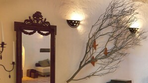 Ein Spiegel mit aufwändigem Rahmen, ein an der Wand befestigter Ast mit Blättern und zwei Wandleuchten.