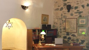 Ein Arbeitsraum mit Schreibtisch, Lampe, Bücherregal und Steinwand.